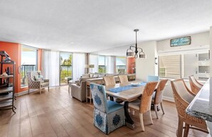 A spacious dining area with a large table and chairs, a balcony with a railing, and a sign on the wall. - GOLF and BEACH PARADISE! Oceanfront 4-bedroom condo in nice North Myrtle Beach. (North Myrtle Beach)