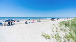 Ein Strand mit Liegestühlen, Sonnenschirmen und einem strahlend blauen Himmel.