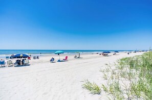 Ein Strand mit Liegestühlen, Sonnenschirmen und einem strahlend blauen Himmel.