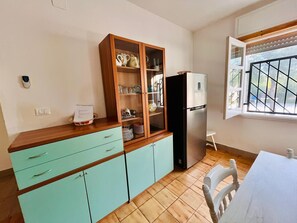 A kitchen with a wooden cabinet, a refrigerator, and a window with a view. - Your corner of paradise just a stone's throw from the sea, among dunes and the scent of Salento 🌾 (Puglia)