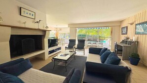 A living room with a fireplace, TV, and seating area. - Villa forêt avec piscine privée | La plage à 2km (Moliets)