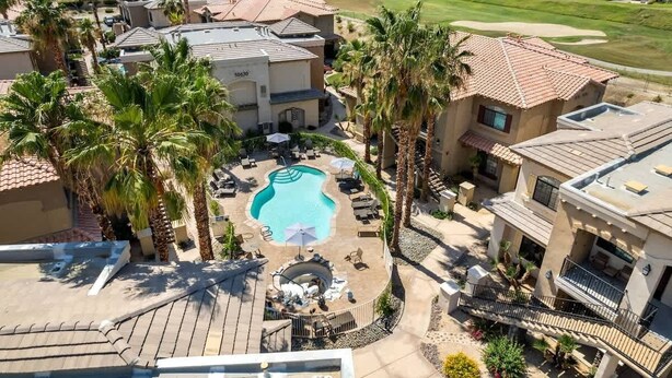 A residential area with a swimming pool, palm trees, and houses with red-tiled roofs. - Golf Course Views - Sleeps 4 - CLR 610-7 (La Quinta)