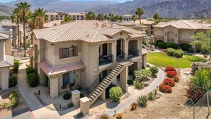 A residential building with a tiled roof, a central staircase, and a landscaped garden with palm trees and shrubs. - Golf Course Views - Sleeps 4 - CLR 610-7 (La Quinta)