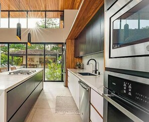 Een moderne keuken met een groot eiland, roestvrijstalen apparatuur en uitzicht op de omgeving.