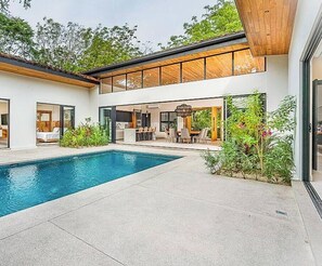 Een modern huis met zwembad, buitenzitplaatsen en een eethoek.