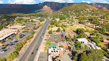 An aerial view of a town with a main road, buildings, and a mountain range in the background.