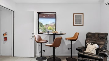 A room with a door, a window with a view, two chairs, a table, and a sofa.