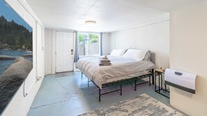 Un dormitorio con cama, una mesita de noche, un calentador de pared y vistas al exterior.
