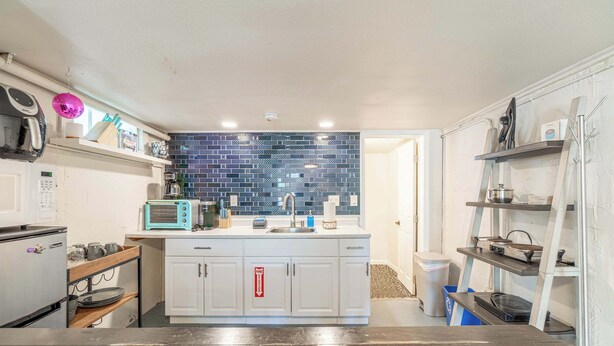 Una cocina compacta con armarios blancos, un salpicadero de azulejos azules y una pequeña encimera.