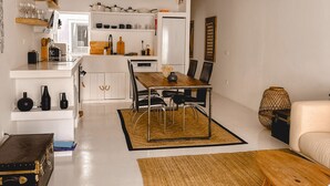 Una cucina moderna con mobili bianchi, un'area pranzo con tavolo e sedie in legno, e una lampada a sospensione.