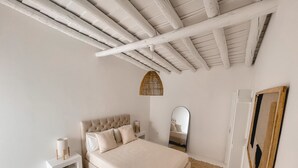 Una camera da letto con un letto, un comodino, uno specchio e un tappeto tessuto.