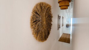 Un corridoio con un'ampia opera d'arte a forma di cerchio sulla parete, un lampadario e un tappeto decorato.