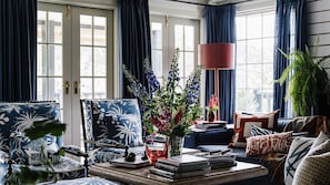 Ein Wohnzimmer mit einer Couch, einem Sessel und einem Couchtisch mit Büchern und einer Blumenvase.