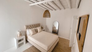 A bedroom with a bed, nightstand, mirror, and a woven rug. - Casa Pura Vida By Gt House (Reguengos de Monsaraz)