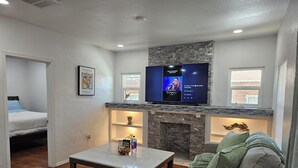 A living room with a fireplace, a television mounted above it, a bed, and a sofa. - Central Close to Downtown, Airport, Fort bliss, Restaurants , Entertainment,UTEP (El Paso)