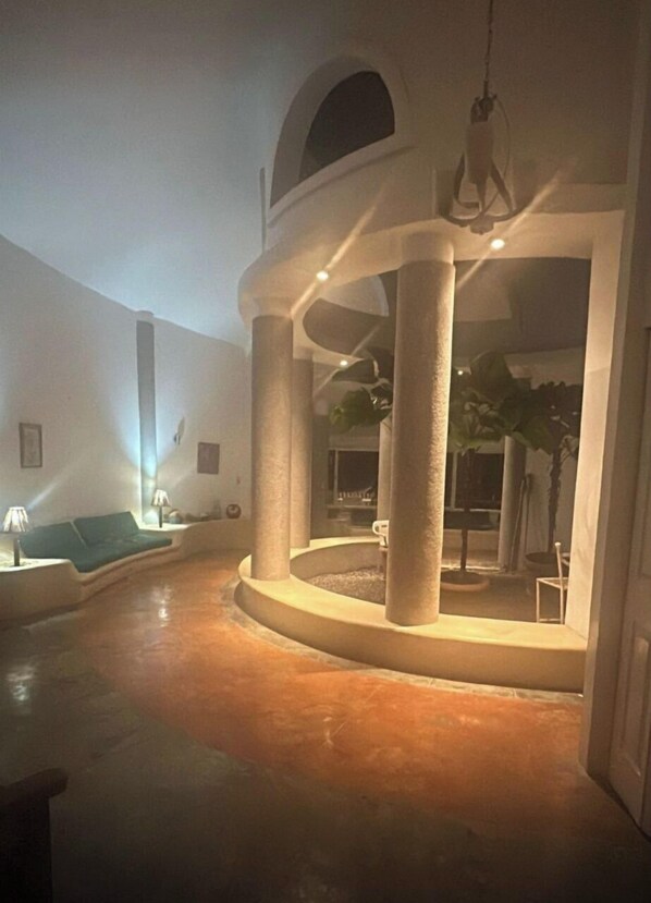 A spacious indoor area with a circular seating arrangement, columns, and a hanging light fixture.
