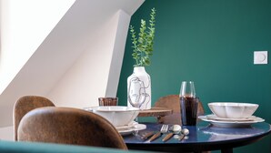 Uma mesa de jantar com um vaso de folhas verdes, um copo de líquido escuro e diversos pratos.