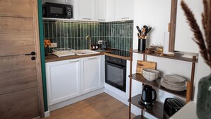 Cozinha com armários brancos, micro-ondas, forno, pia e cafeteira.