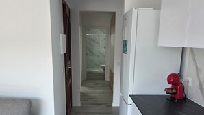 Ett modernt kök med en grå soffa, ett trägolv och en röd köksapparat på bänkskivan.