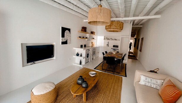 A modern living room with a flat-screen TV, a sofa, a coffee table, and a dining area with a table and chairs. - Casa Pura Vida By Gt House (Reguengos de Monsaraz)