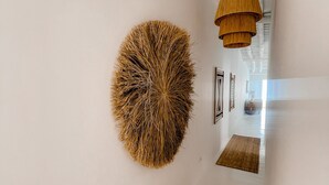 A hallway with a circular wall art, a woven rug, and a hanging light fixture. - Casa Pura Vida By Gt House (Reguengos de Monsaraz)