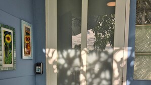 Una porta con pannelli di vetro smerigliato, un citofono a parete e due quadri incorniciati.