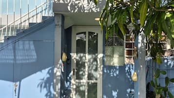 A blue building with a glass door, a staircase, and a small garden with artificial grass and metal chairs.