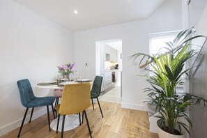 A dining area with a round table, four chairs, and a potted plant. - Stylish Two-Bed Cheltenham Retreat with Hot Tub (Cheltenham)