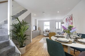 A modern kitchen with a dining area, a staircase, and a large potted plant. - Stylish Two-Bed Cheltenham Retreat with Hot Tub (Cheltenham)