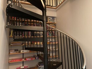 Eine Wendeltreppe mit Bücherregalen auf jeder Ebene, einem Metallgeländer und einem Teppichboden.