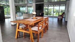 A wooden dining table with six chairs, a vase with white flowers, and a view of a balcony with a railing. - SANTA RITA FARM (MORELIA)
