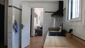 A modern kitchen with a wooden countertop, a black range hood, and a window. - Thieman House - MENTON (MENTON)