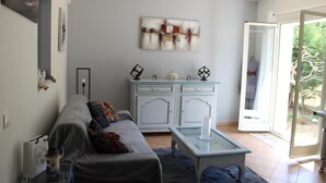 A living room with a sofa, a glass coffee table, a cabinet, and a painting on the wall. - Thieman House - MENTON (MENTON)