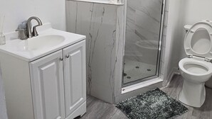 Ein Badezimmer mit Dusche, Waschbecken, Toilette und einem dekorativen Teppich.