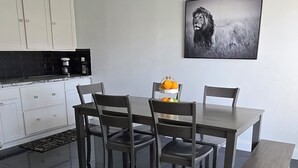 Eine moderne Küche mit weißen Schränken, einer schwarzen Arbeitsplatte und einem Essbereich mit Tisch und Stühlen.