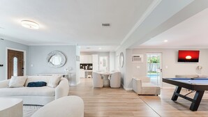 Ein modernes Wohnzimmer mit Billardtisch, einer Couch und einem Essbereich.