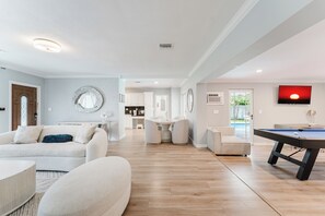 Ein modernes Wohnzimmer mit Billardtisch, einer Couch und einem Essbereich.