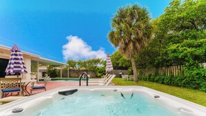 Ein Whirlpool mit Pool, Gartenmöbel und ein Holzzaun.