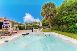 Ein Whirlpool mit Pool, Gartenmöbel und ein Holzzaun.