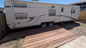 Een recreatiewoning in een achtertuin, met een houten terras ervoor.