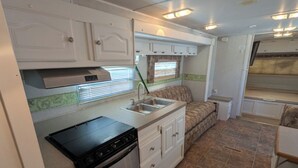 Een kleine keuken voor een camper, met een fornuis, spoelbak en kastjes.