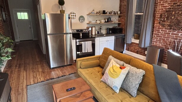 A compact living space with a sofa, coffee table, and a kitchenette. - Benton Park Walkable Apartment- IN1S (St. Louis)
