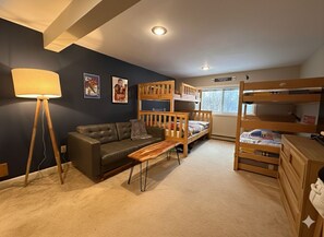 Une pièce comprenant un lit superposé, un canapé, une table basse, une lampe et une commode.