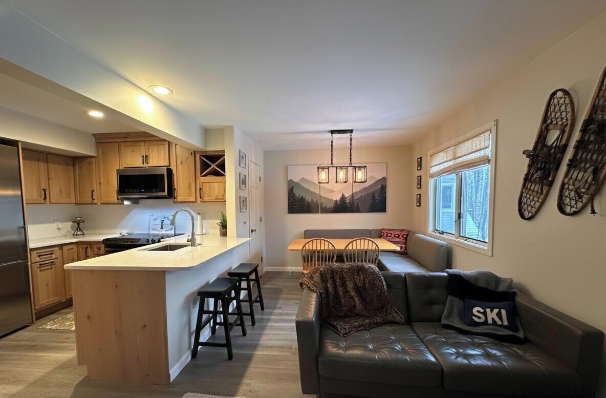 A modern kitchen with wooden cabinets, a central island, and a dining area with a bench and chairs.