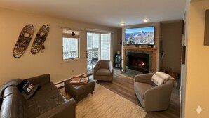 A living room with a fireplace, a television, and a view of mountains through the window. - Cozy 3-bedroom townhome in West Dover, steps from the magic carpet (Dover)