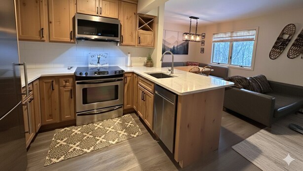 A kitchen with wooden cabinets, stainless steel appliances, a dining area with a sofa, and a large window. - Cozy 3-bedroom townhome in West Dover, steps from the magic carpet (Dover)
