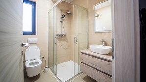 Een moderne badkamer met een glazen douchecabine, een wit toilet, een houten wastafelmeubel en een grote spiegel.