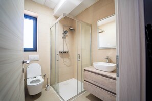 A modern bathroom with a glass-enclosed shower, a white toilet, a wooden vanity, and a large mirror. - Villa Isabel Azure  (Matulji)