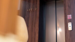 Een lift met houten paneel en een bordje met 'APT 2'.