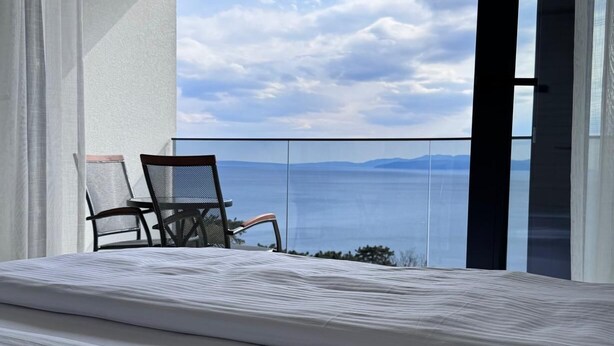 Een balkon met een bed, een stoel en een tafel.